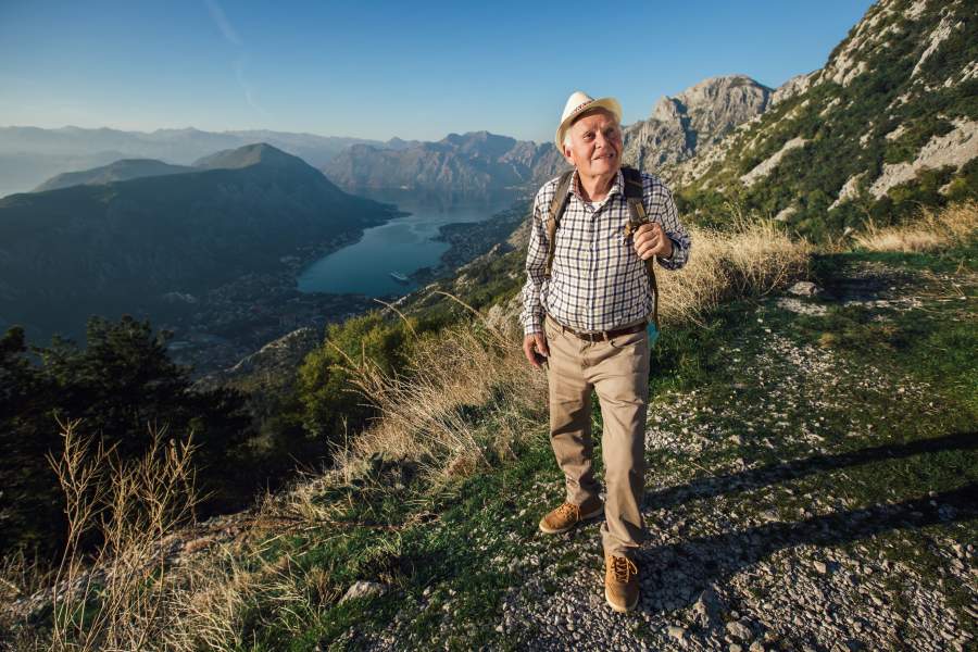 Senior man climbing mountain peak on 2020 holiday