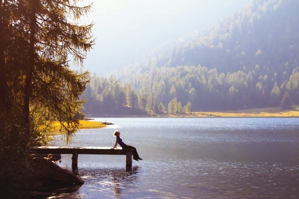 Woman sitting on the dock of a lake contemplating life