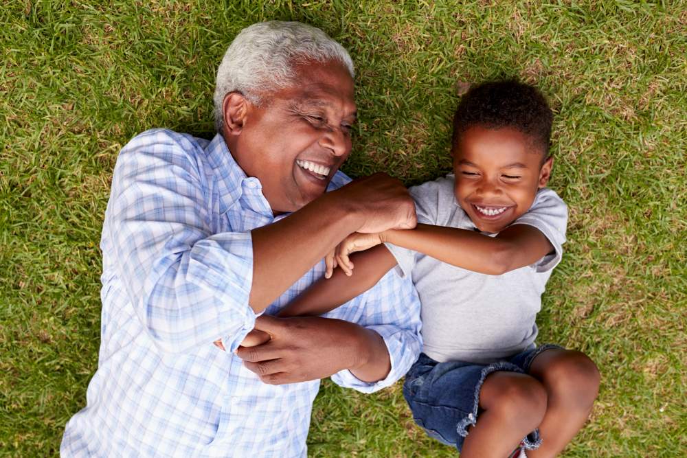 Grandfather and grandson laying down on on the grass having fun