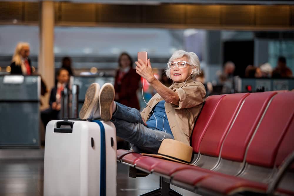 Can I Fly after a Stroke? Old woman sitting at the airport taking a selfie