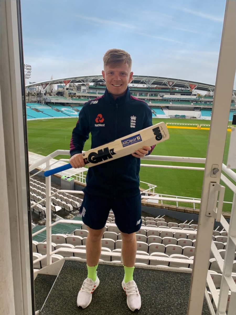 Oliver Pope holding AllClear sponsored ciricket bat