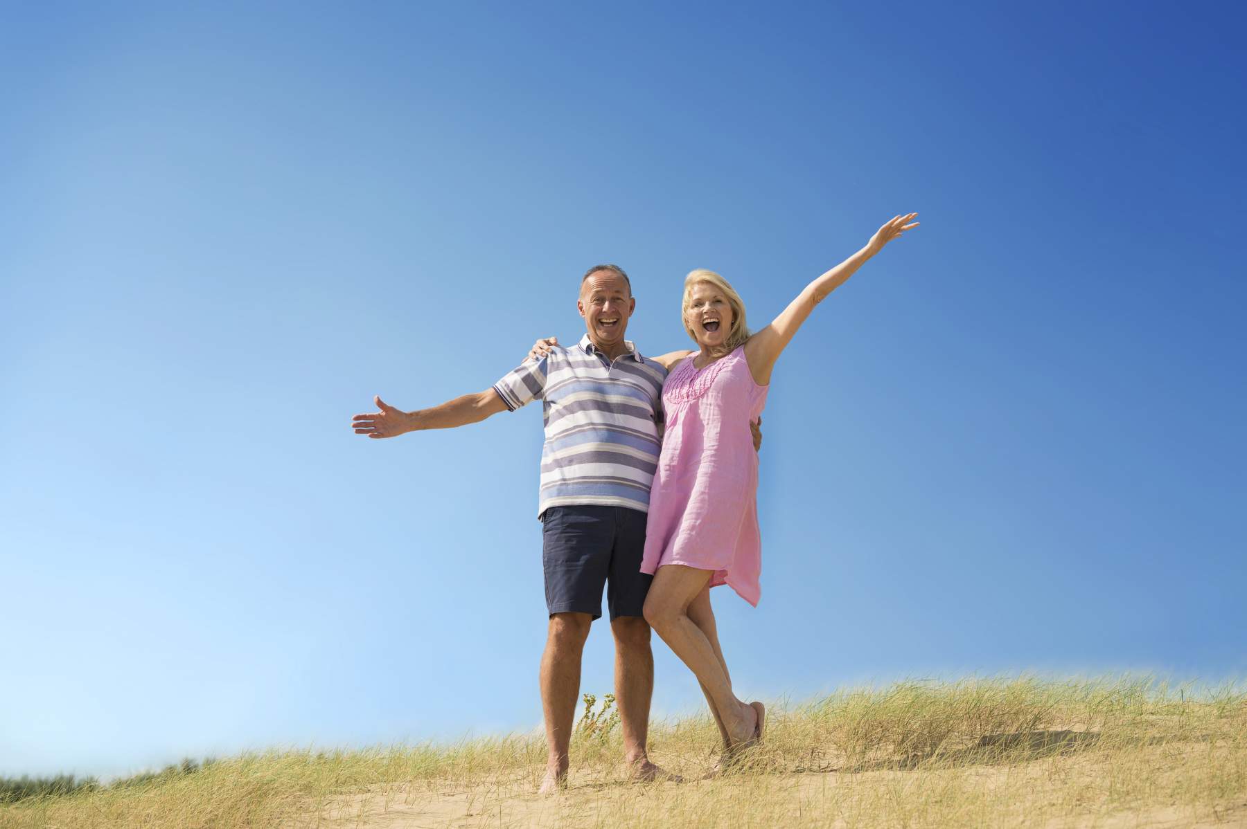 Happy couple with their hands in the air on holiday as Money Saving Expert Martin Lewis Makes 2020 Travel Insurance Plea