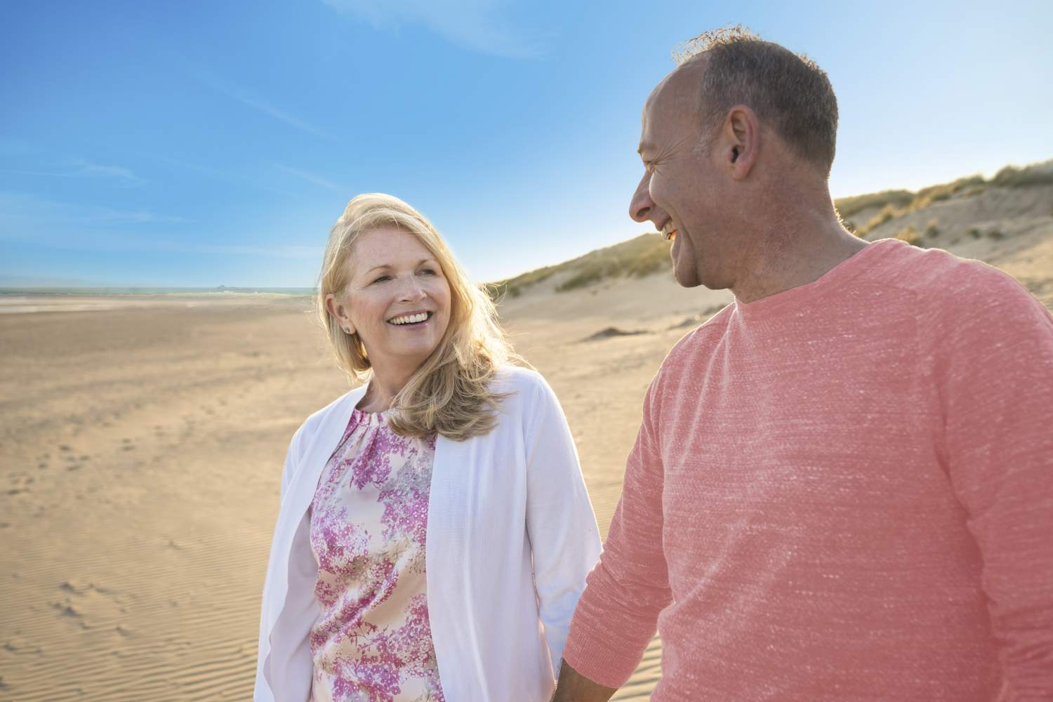Mature happy couple on beach who have mental health travel insurance