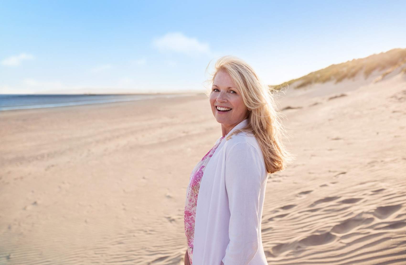Mature woman strolling on beach as Money Saving Expert Martin Lewis Makes 2020 Travel Insurance Plea