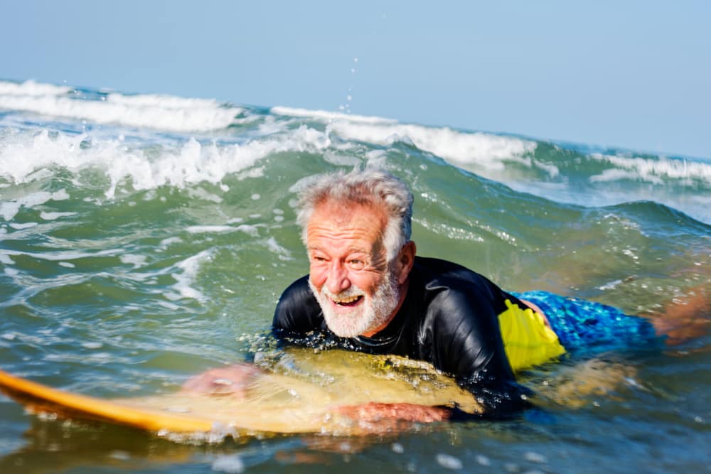 Travelling with a mental health condition: Old man surfing in the sun