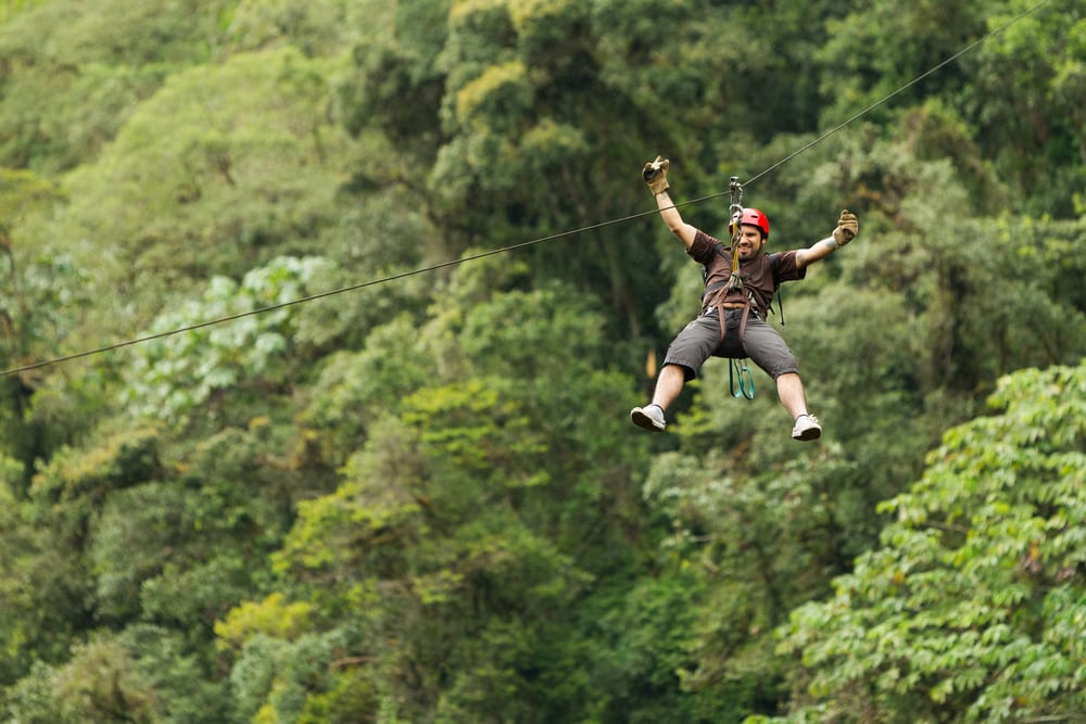 Why a bucket list is so important and how to plan one: Middle aged man on zip line adventure in Ecuadorian Rainforest