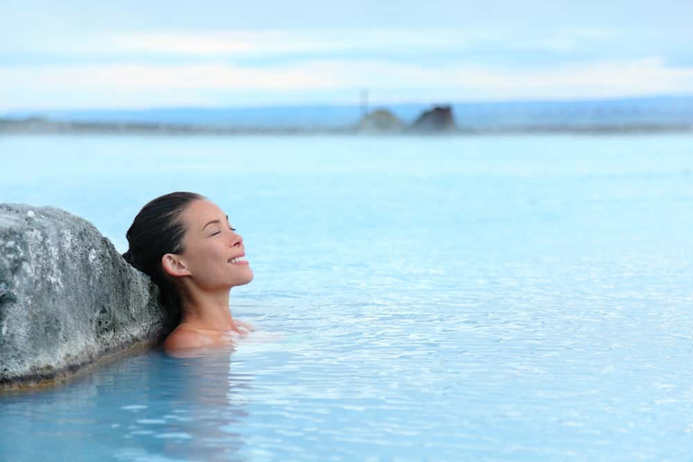 Top 10 safest countries to visit in the world 2018: young woman bathing in hot springs in Iceland 