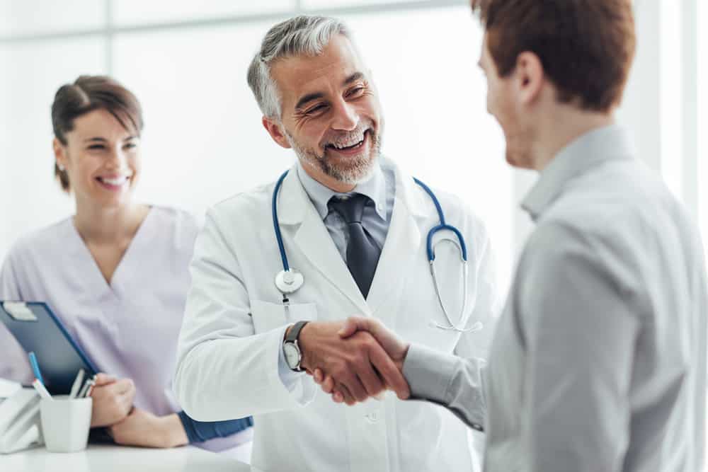 Do I Need Travel Insurance? Is It Worth It? Doctor shaking hands with patient