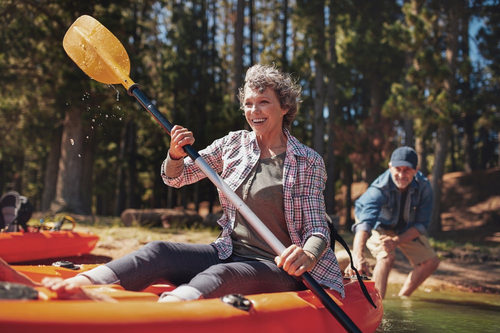 Travelling with a mental health condition: Happy middle aged woman kayaking